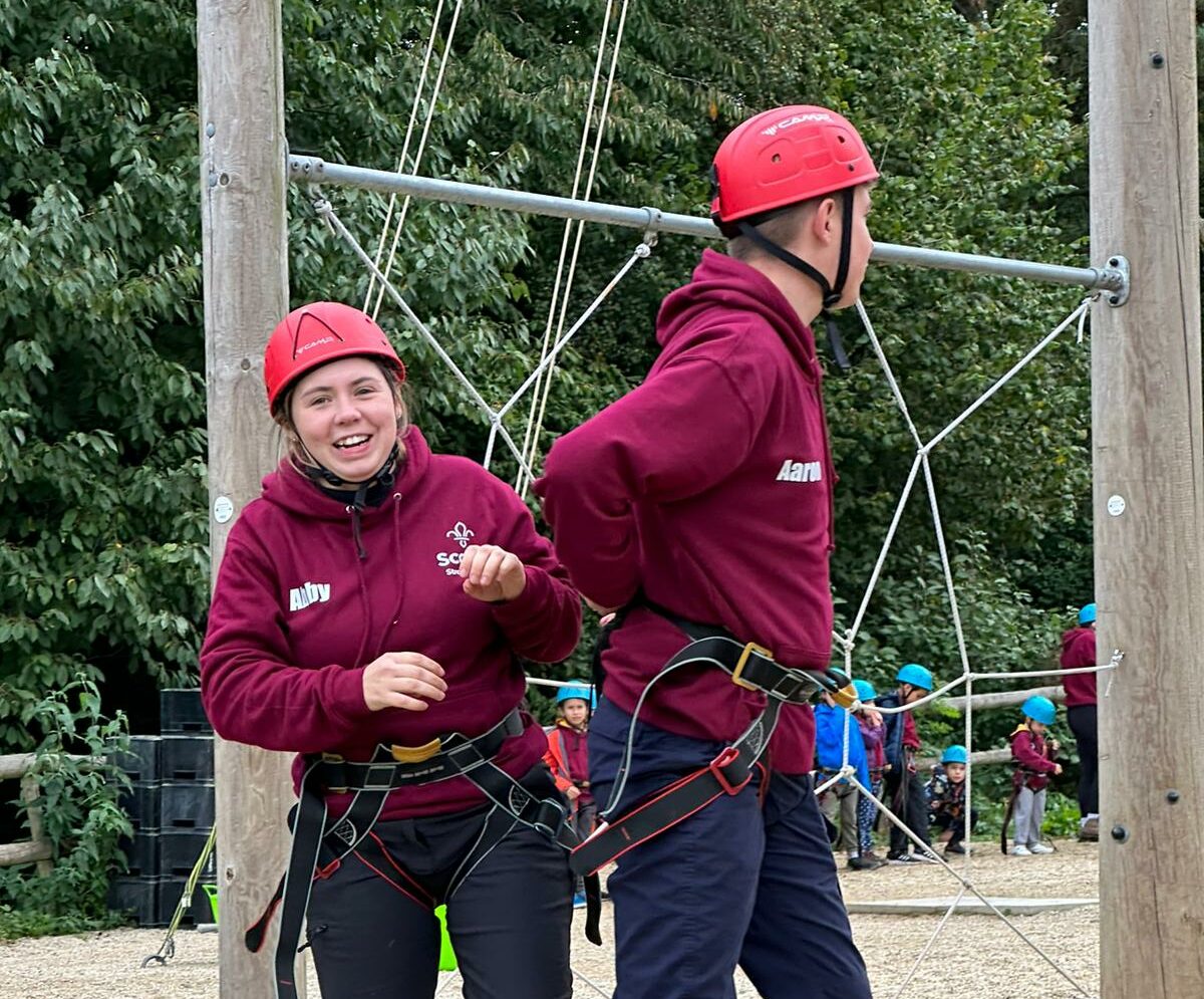 Scout leaders from Stroud Valley Scout Group helping prepare harnesses for a climbing activity on camp